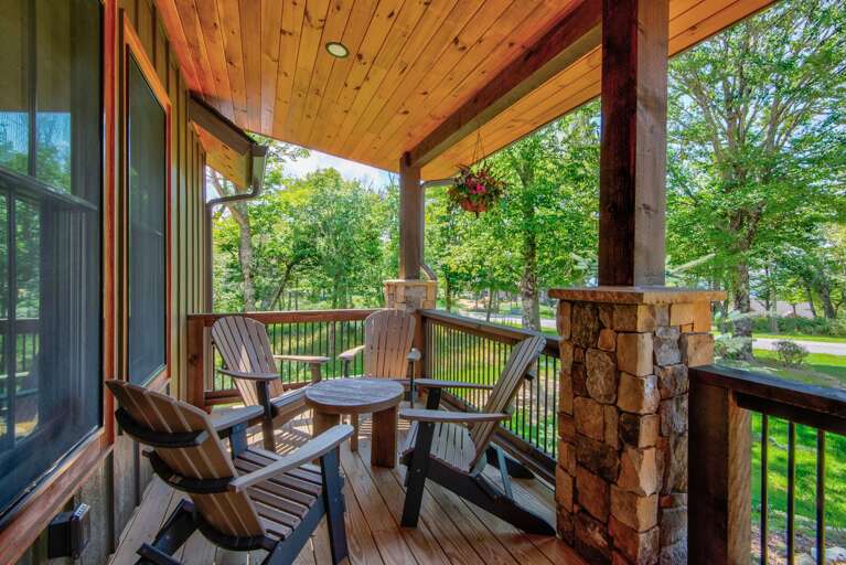 Settle in and take it slow on the covered porch at The Sugar Chalet, surrounded by wooded views and hanging blooms.