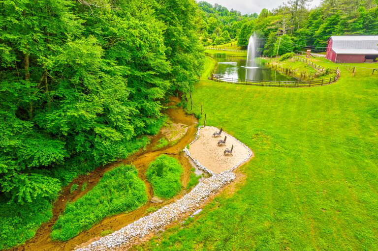 Creekside beach with a soaring fountain and the iconic red barn. Pure Blue Ridge charm.