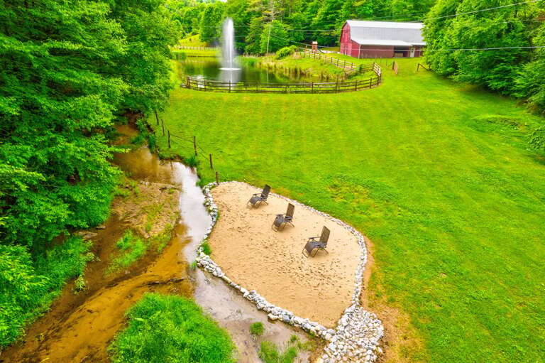 Creekside beach with a soaring fountain and the iconic red barn. Pure Blue Ridge charm.