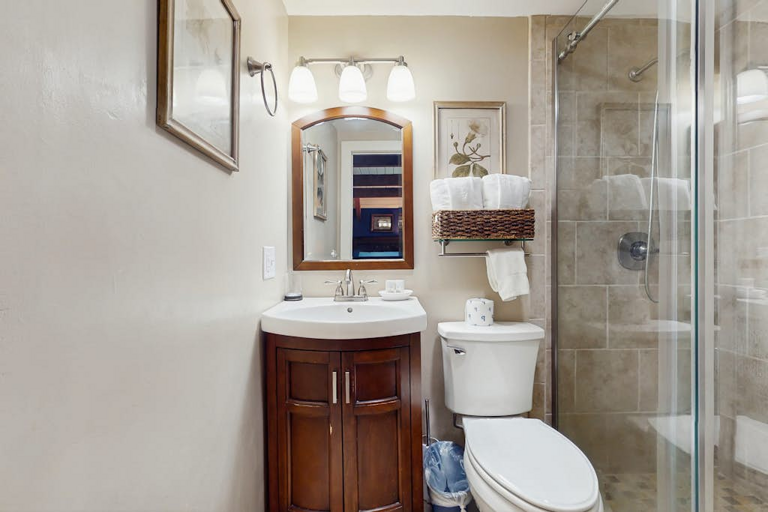 A full bathroom with a single vanity top and a glassed in tile shower