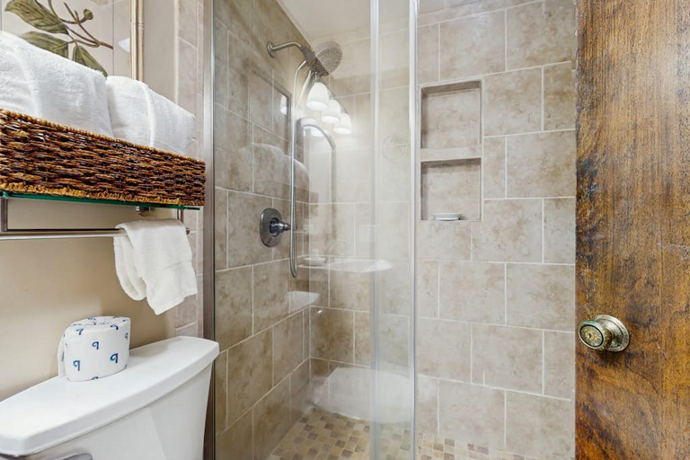 A full bathroom with a single vanity top and a glassed in tile shower