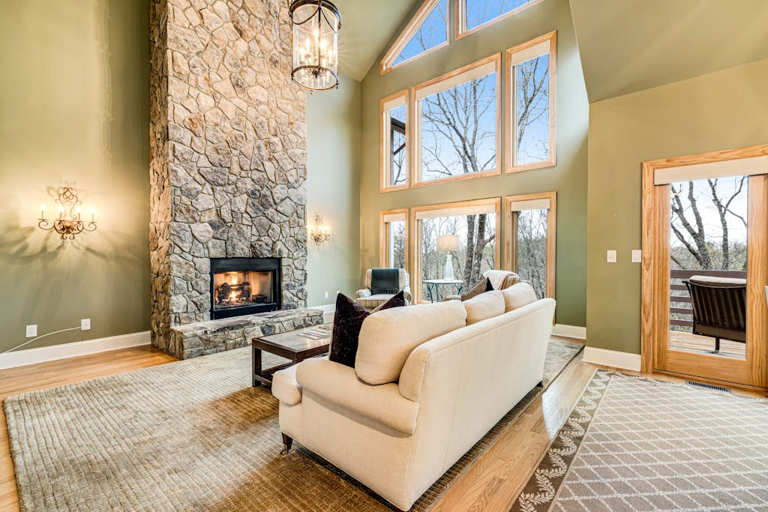 Soaring windows and a dramatic stone fireplace create a warm, inviting mountain living space.