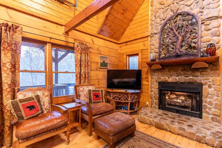 Rustic Room With Stone Fireplace, Timber Walls, Plush Seating, Vibrant Cushions, And Television