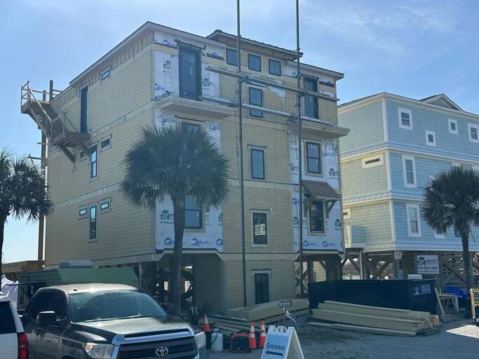 Tall Tan Building Under Construction With Palm Trees And Parked Truck