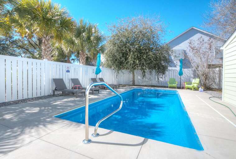 Sunny Swimming Spot With Shimmering Water, Surrounded By Chairs And Trees