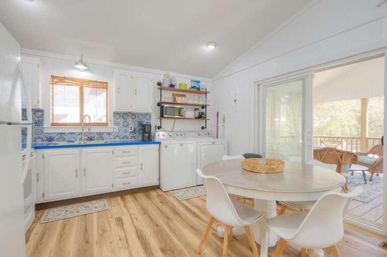 Kitchen With Wooden Floor, Round Table, White Chairs, Blue Backsplash, Sliding Glass Door