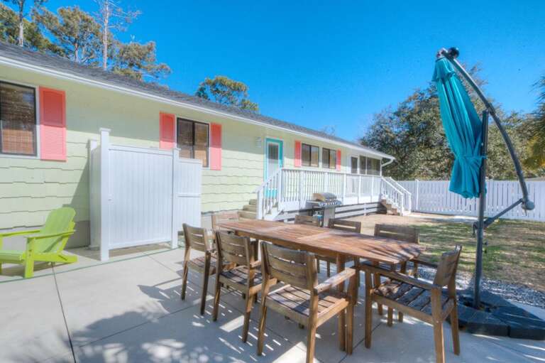 Patio With Wooden Table, Chairs, Umbrella, And Fence