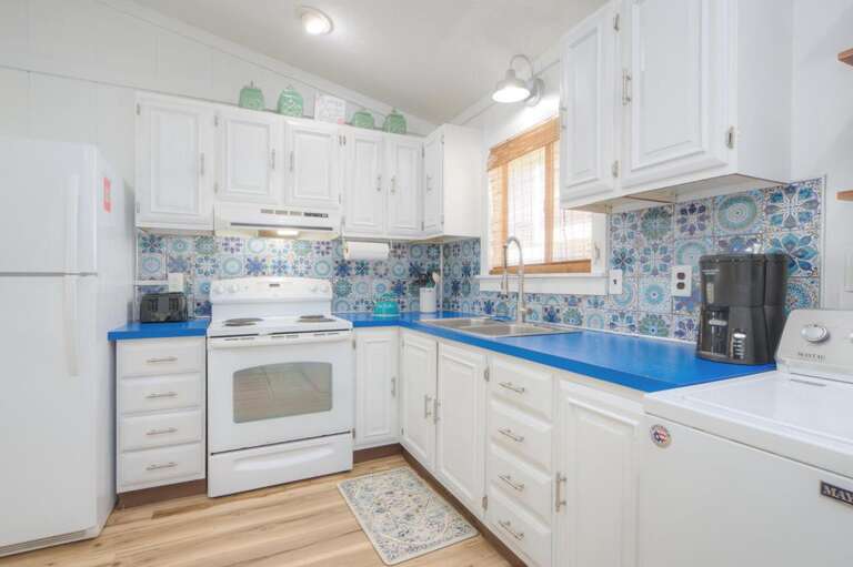 White Kitchen With Blue Countertops, Floral Backsplash, And Wooden Floor