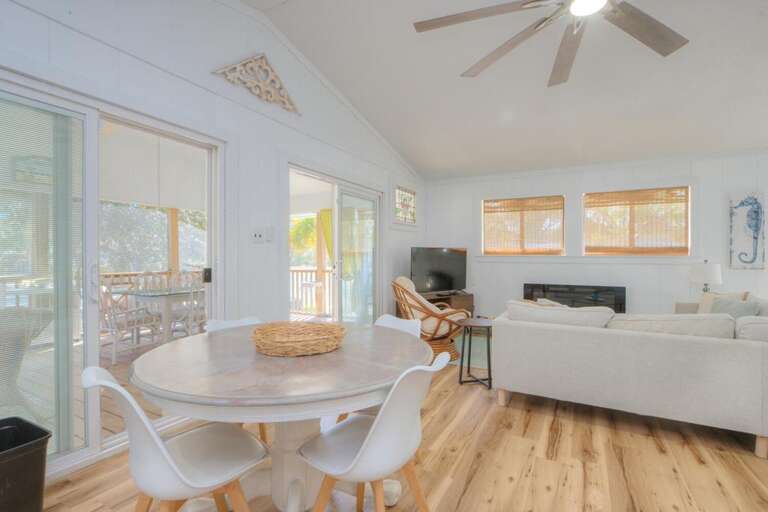 Bright Living Area With Round Dining Table, White Chairs, And Large Windows