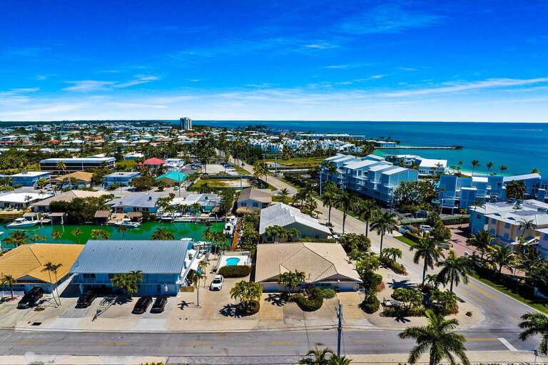 Aerial View Of Tropical Seaside Town With Palm-lined Streets And Bright Blue Ocean