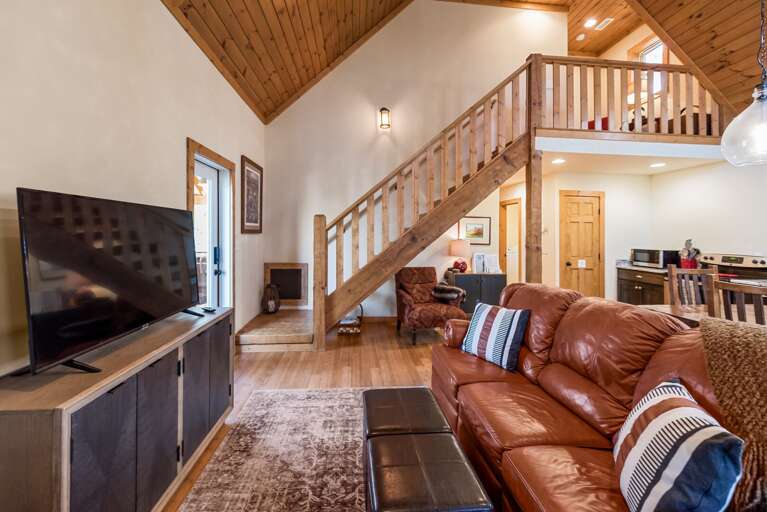 Living Room With Large Leather Sofa, Wooden Stairs And Loft Above