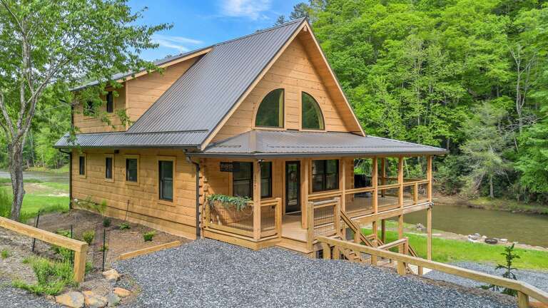 Wooden House By Water With Wide Windows And Wraparound Porch