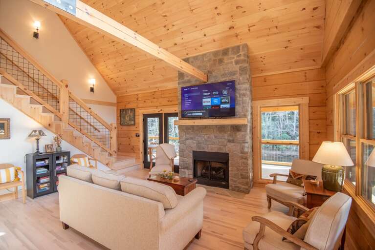 Spacious Living Space With Staircase, Stone Fireplace, And Large Windows