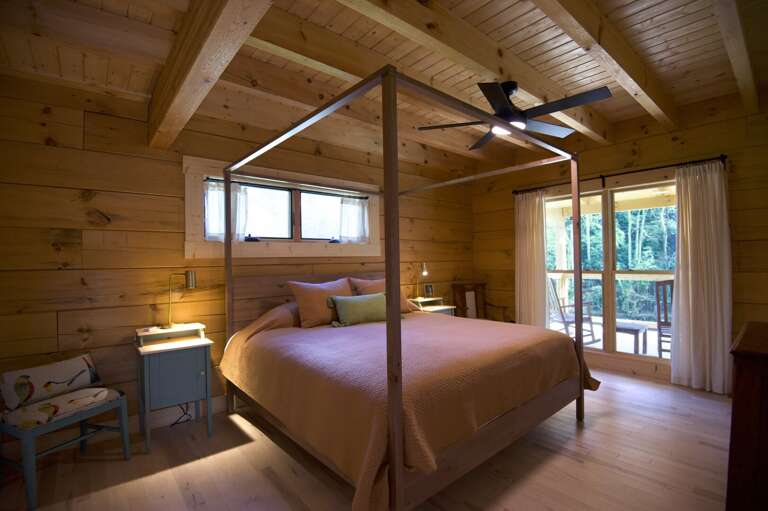 The peaceful master bedroom suite overlooks the porch and river