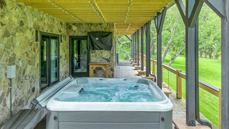 Stone Structure With Jacuzzi On Covered Patio Overlooking Lush Lawn