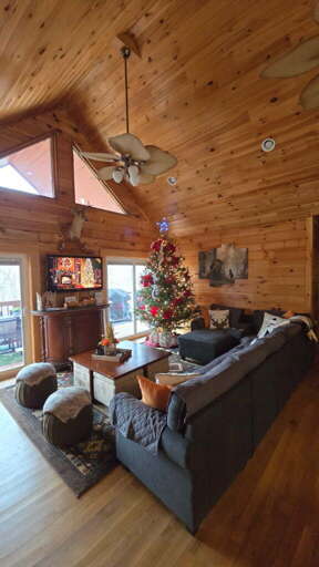 Wood-wrapped Room With Christmas Tree, Gray Sofa, And Ceiling Fan