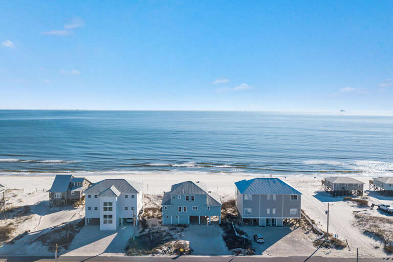 Seaside Houses Near Sandy Shore Under Blue Sky
