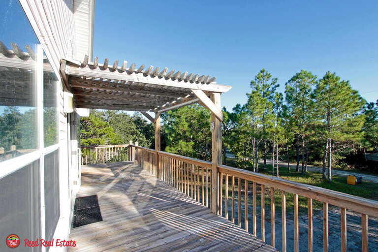 Sunlit Wooden Deck With Pergola Overlooking Pine Trees