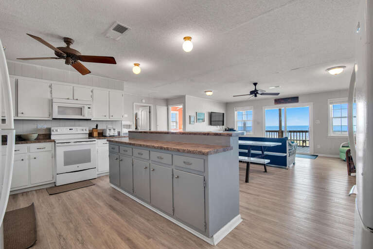 Spacious Indoor Scene Showing Kitchen Leading To A Bright, Breezy Balcony With Seaside View