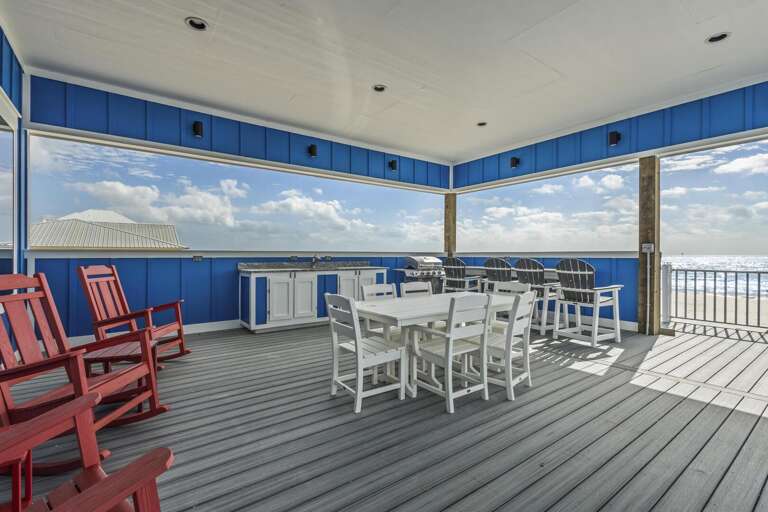 Vacation Rental Balcony With Blue Beams, Grey Deck, Red Chairs, And Scenic Sea Views