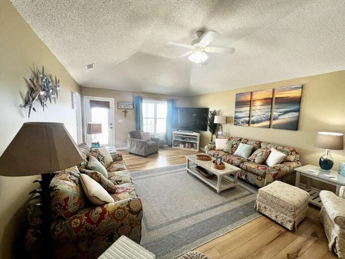 Living Room With Plush Seating, Central Ceiling Fan, And Large Artwork