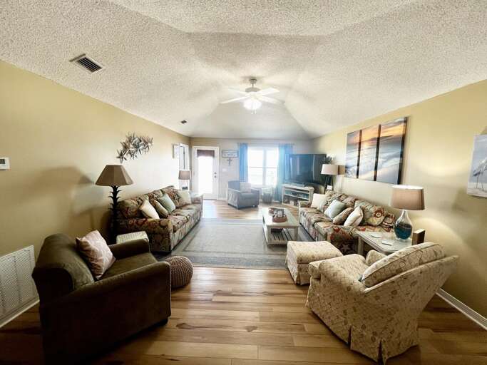 Living Space With Sofas, Wooden Floors, And Lamps, Leading To A Luminous Window
