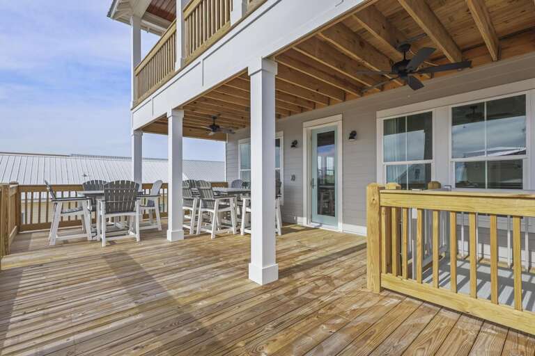 Sunlit Seaside Structure With Sprawling Deck And Dining Chairs
