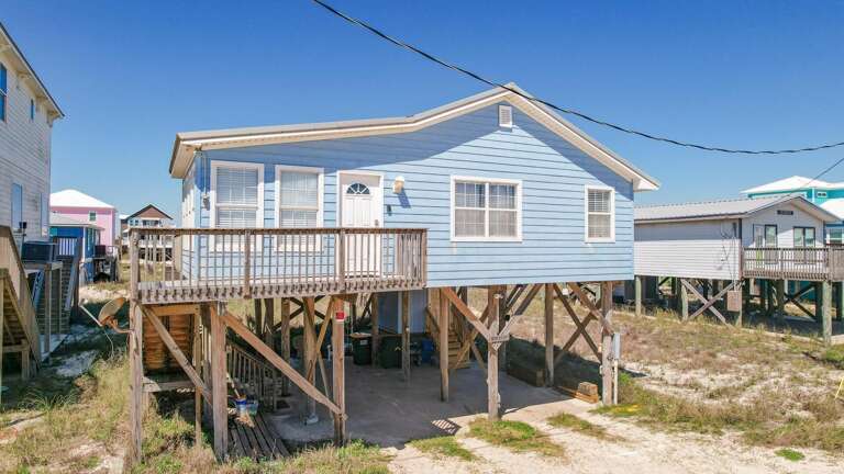 Raised Blue Beach House On Stilts, Surrounded By Similar Structures