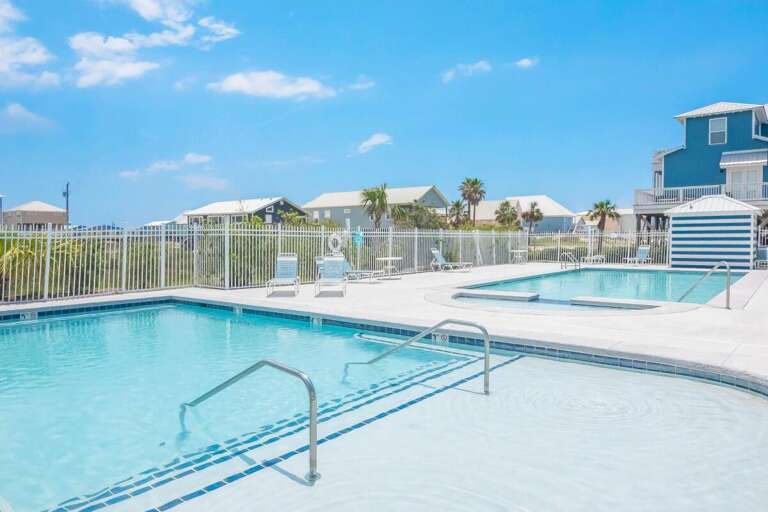 Blue Pool By Beachside Homes Under Bright Sky