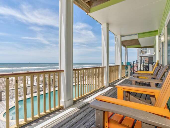 Seaside Vacation Rental Balcony With Wooden Chairs Overlooking The Beach