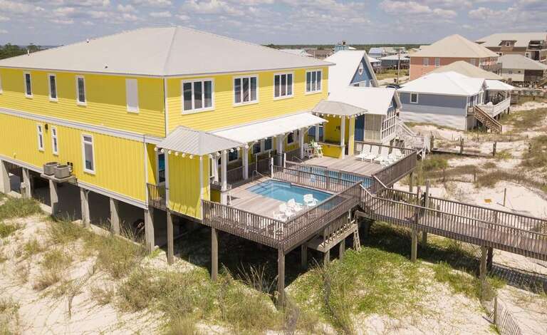 Beachfront Building With Balcony And Boardwalk, Vibrant Yellow Siding Under Sunny Skies
