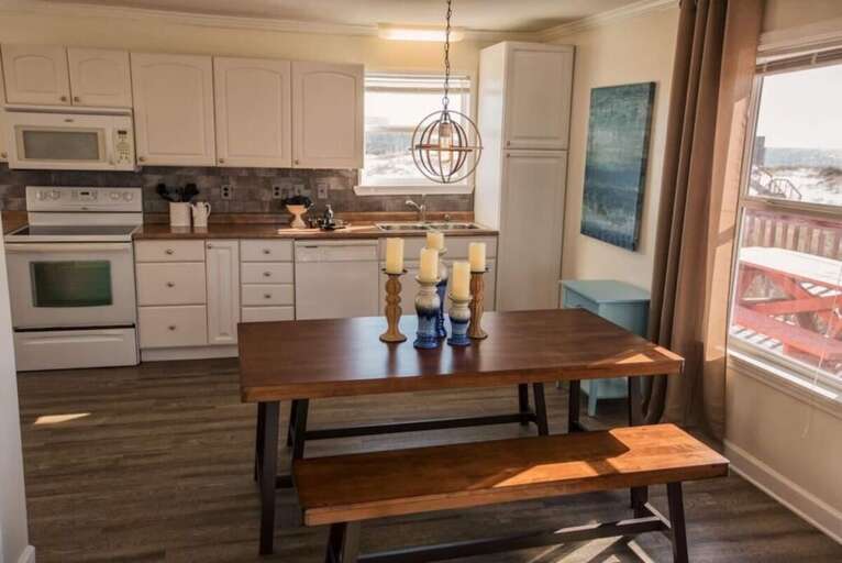 Interior Kitchen Space With Wooden Dining Setup And White Cabinetry Under Soft Sunlight