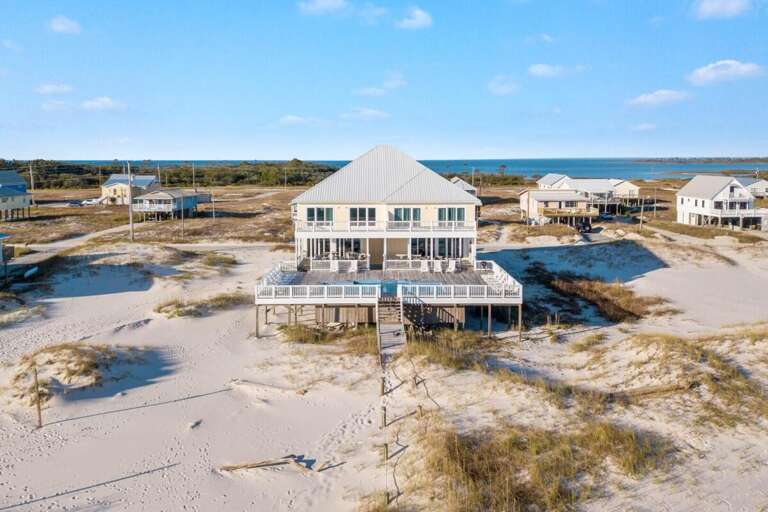 Seaside Structure Stands Surrounded By Sand, Sky, And Sparse Settlements