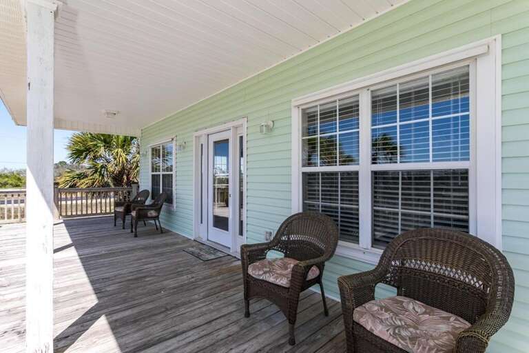 Patio Of Pale Green Home With Wicker Chairs And Open Sliding Door
