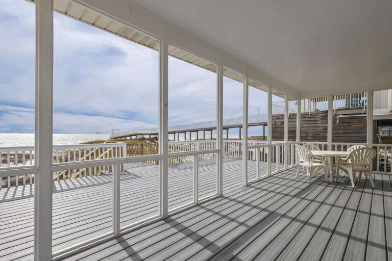 Bright Balcony Facing Beach With Breezy, Broad Windows And Bleached Wooden Floor