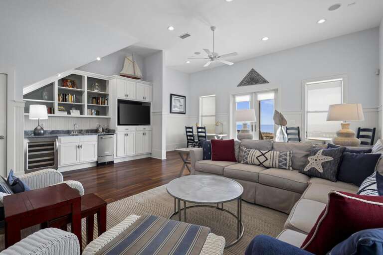 Bright, Breezy Living Space With Sectional Sofa, Circular Table, Built-in Shelves, And Kitchen View