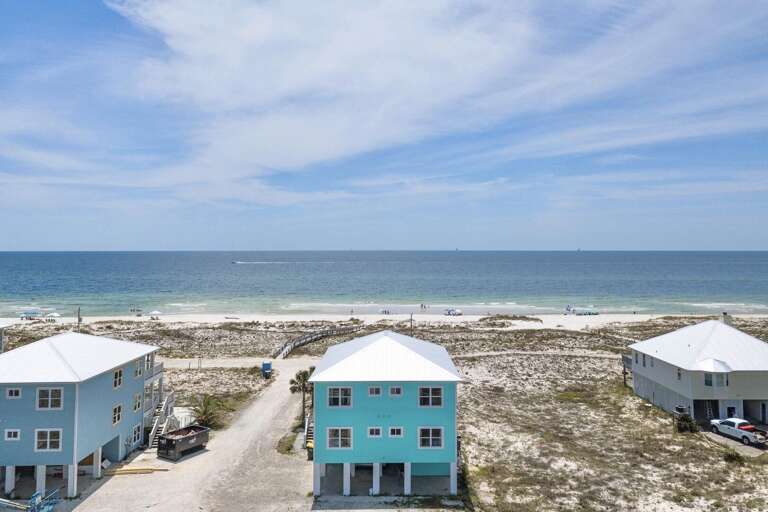Seaside Structures Sandwiched Between Sandy Shore And Azure Sky