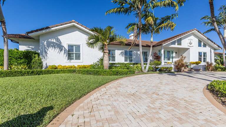 White-walled Residence Ringed By Radiant Palms, Paved Path Leading Up